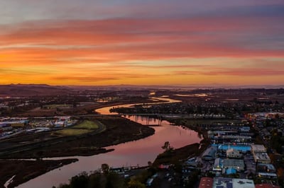 The Napa River at dusk from the air, winding under a highway bridge and through town, Napa, California