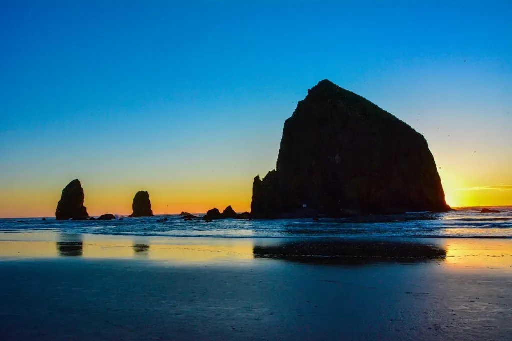 Haystack Rock and the Needles silhouetted against the sunset at Cannon Beach, Oregon