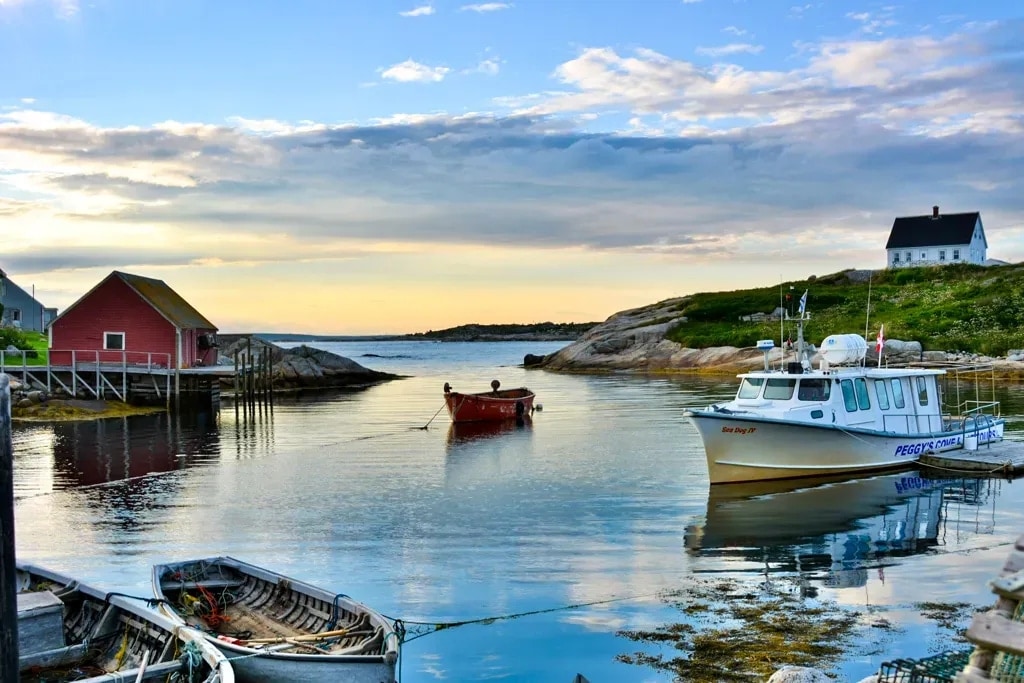 A red fishing shack, moored boats, and wooden dories on still water at Peggy's Cove, Nova Scotia