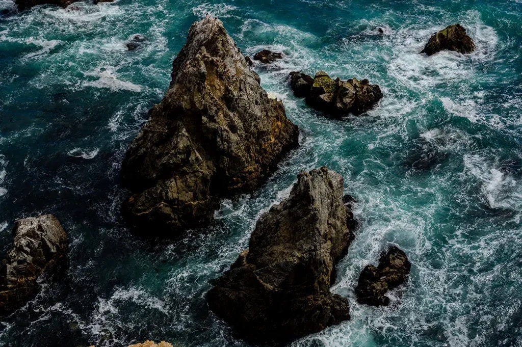Waves swirling against rugged rocks along the California coast