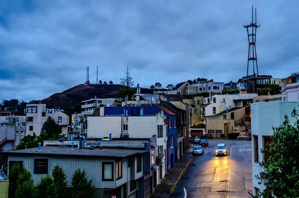 Sutro Tower above a residential street at dusk under heavy clouds, San Francisco
