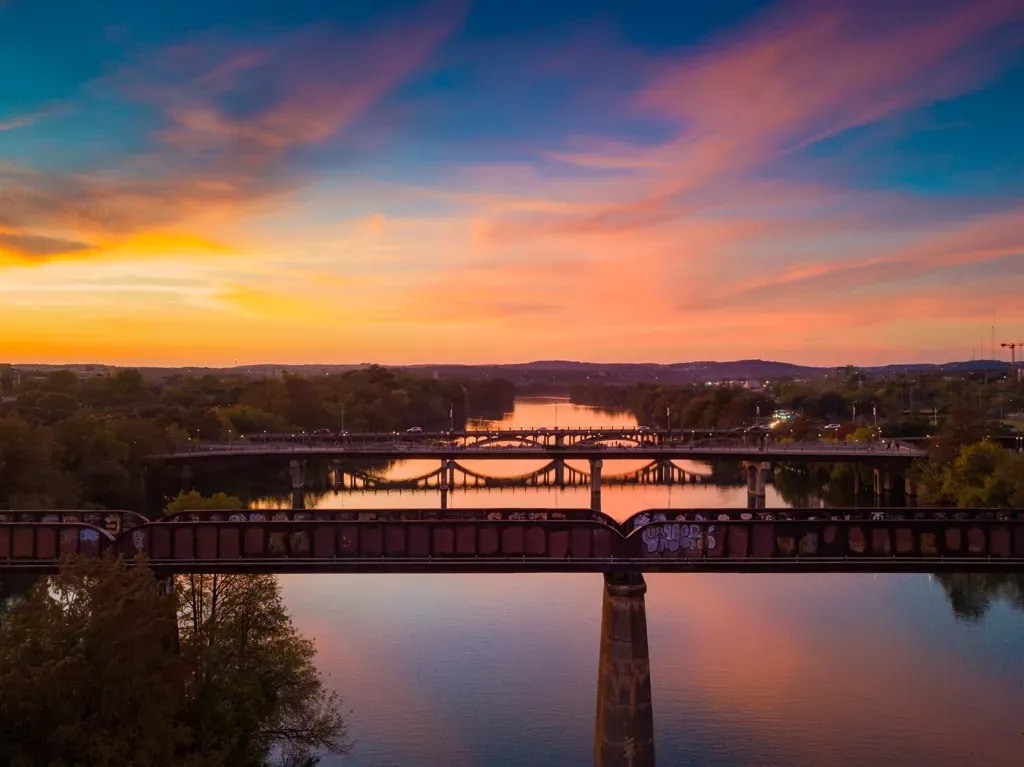 Three bridges crossing Lady Bird Lake at sunset, a railroad trestle in the foreground, Austin, Texas